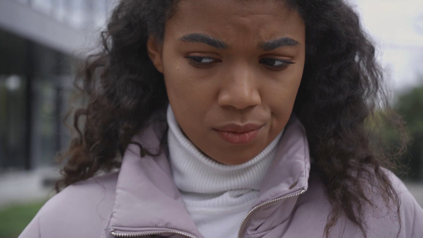 smutný africký americký žena v puffer bunda na ulici - Záběry, video
