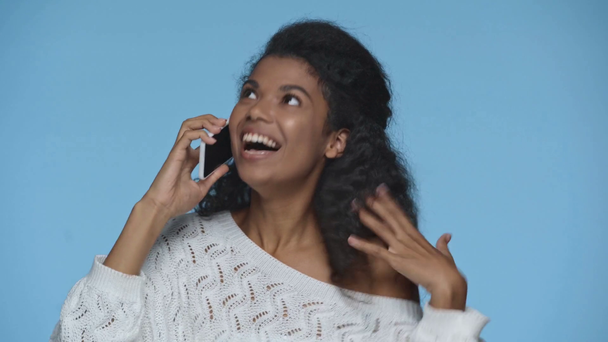 boldog afro-amerikai nő beszél okostelefon elszigetelt kék - Felvétel, videó