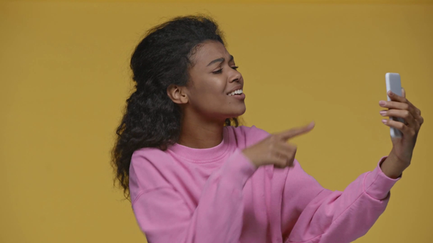 positiivinen afrikkalainen amerikkalainen tyttö ottaa video chat älypuhelin eristetty keltainen
 - Materiaali, video