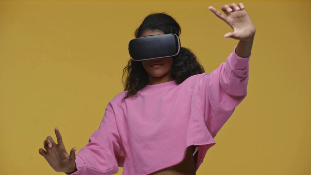 african american girl in vr headset gesturing isolated on yellow - Materiaali, video