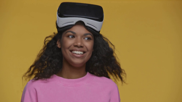 happy african american girl in vr headset dancing isolated on yellow - Footage, Video