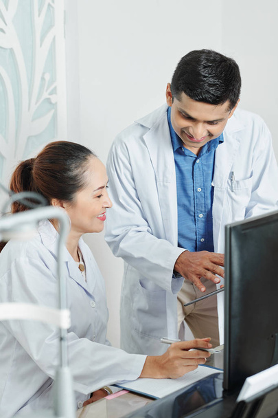 Couple multiethnique de médecins discutant d'une maladie ensemble en utilisant une tablette numérique au bureau
 - Photo, image