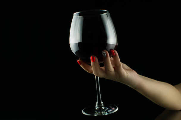 Female hand holding glass of wine on black background - Photo, image