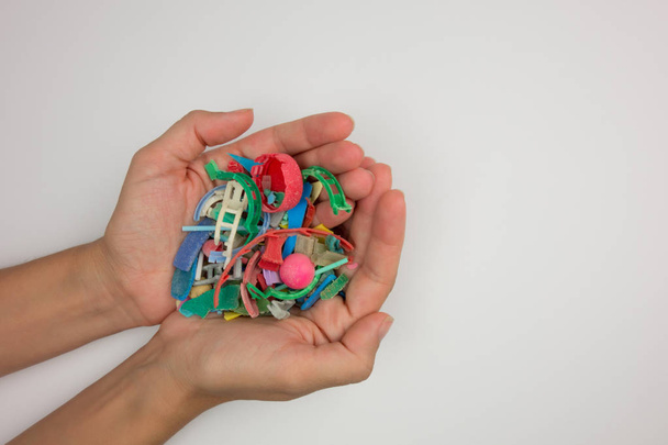 Hands full of microplastics collected on the beach. Plastic pollution concept. - Photo, Image
