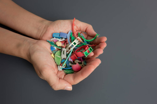 Ruce plné mikroplastů shromážděných na pláži. Koncept znečištění plastem. - Fotografie, Obrázek