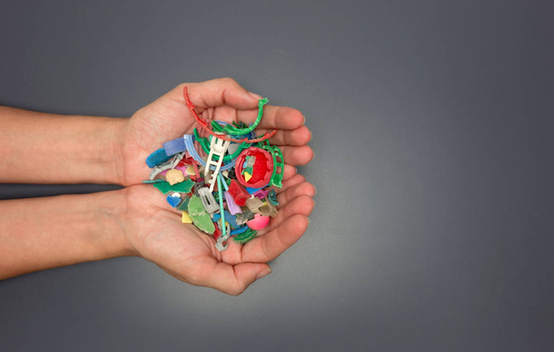 Hände voller Mikroplastik, die am Strand gesammelt wurden. Konzept zur Plastikverschmutzung. - Foto, Bild