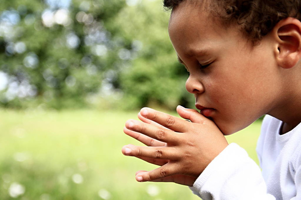 little boy praying to God stock image with hands held together stock photo - Photo, Image