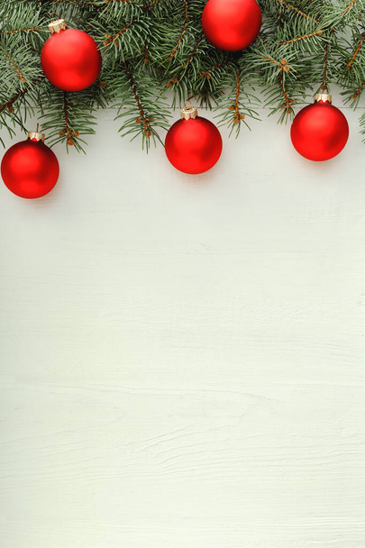 Xmas New Year 2020 holiday celebration pattern composition made of red balls, fir branches on white wooden background. Concept Christmas time, winter. Flat lay, top view, copy space, Instagram story - Photo, Image