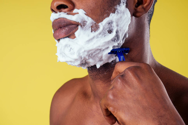Homem afro-americano com navalha e espuma de barbear em seu rosto
 - Foto, Imagem