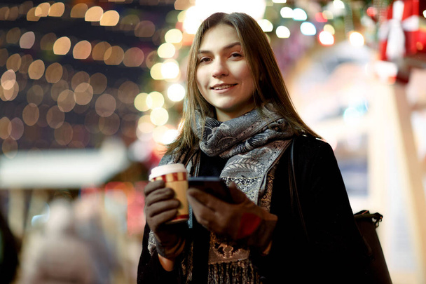 Photo of happy woman with glass and phone in hands in evening for walk - Fotó, kép