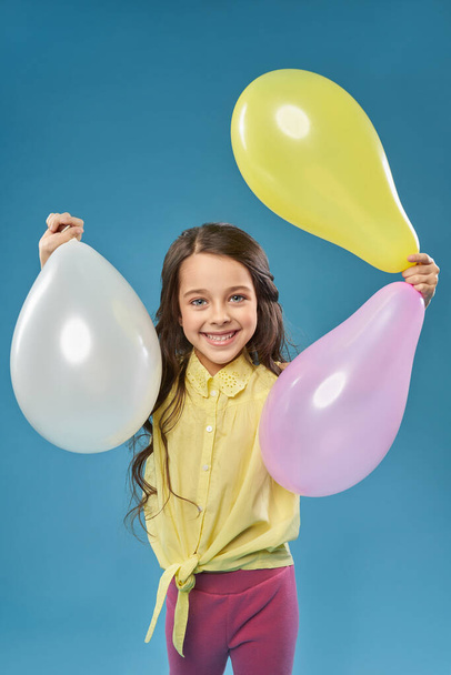 Front view of cheerful girl keeping colorful balloons - Foto, imagen