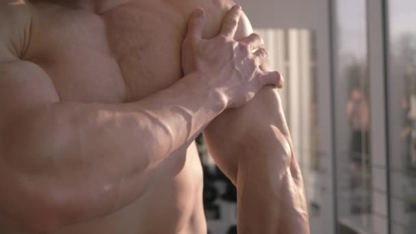 επαγγελματική bodybuilding, αθλητικός άνθρωπος θεωρεί το αποτέλεσμα της άσκησης δύναμης στην οικοδόμηση των μυών στο γυμναστήριο στο φυσικό φως - Πλάνα, βίντεο