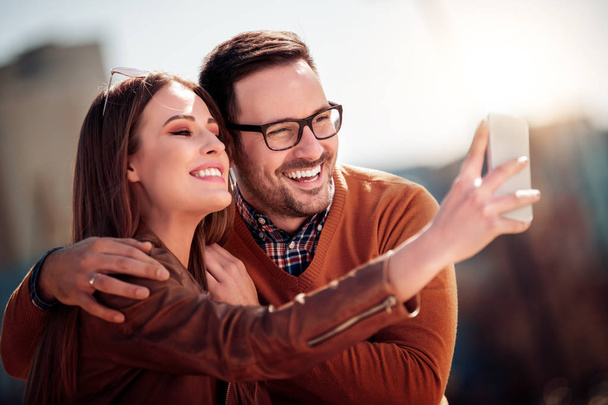 glückliches Paar beim gemeinsamen Selfie in der Stadt an einem sonnigen Tag. - Foto, Bild
