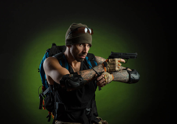 Mann mit Waffe und Rucksack auf dunklem Hintergrund - Foto, Bild