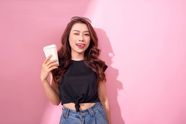 Fashion pretty woman with coffee cup wearing black  clothes over colorful pink background - Photo, image