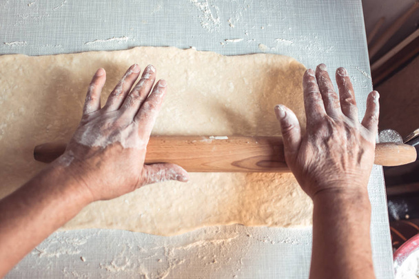 Manos femeninas usando rodillo de masa. Proceso de fabricación de rollos de croissant
 - Foto, Imagen