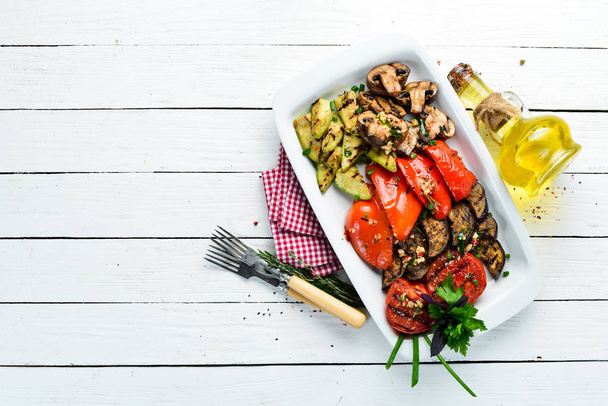 Grilled vegetables on a plate. Tomatoes, eggplants, mushrooms, zucchini. Dishes, food. Top view. Free space for your text. - Zdjęcie, obraz