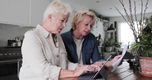Mature lesbian couple looking at digital tablet together at home - Materiaali, video