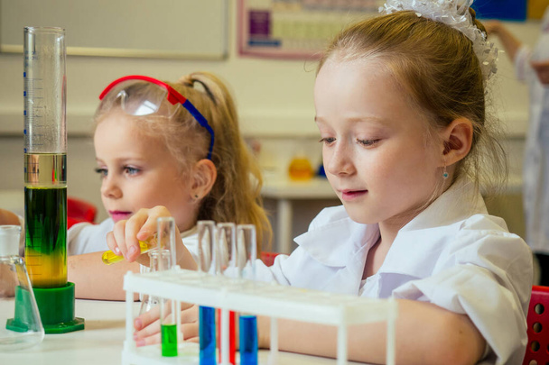 two blonde chemist school kid student little girls girlfriend sisters chemical experiment white medical gown classroom science - Foto, immagini