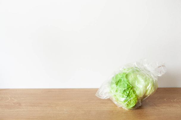 Айсберг салат овощ в пластиковом пакете. одноразовый пластиковый пакет
 - Фото, изображение