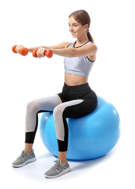 Sporty young woman training with dumbbells and fitball against white background - Fotografie, Obrázek