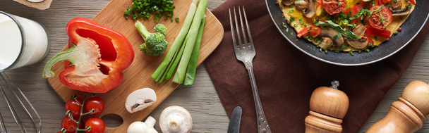vrchní pohled na domácí omeletu v pánvi se zdravými ingrediencemi na stole - Fotografie, Obrázek