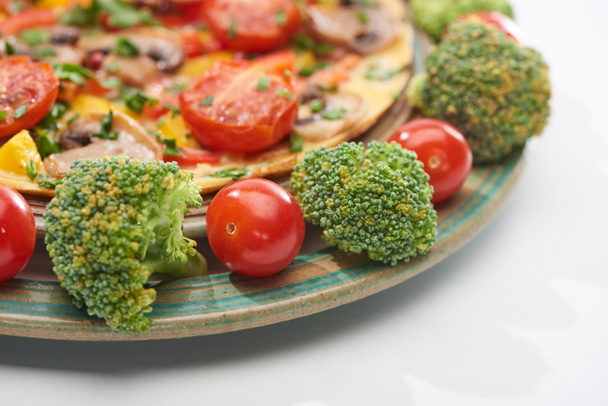 el primer plano de la tortilla en el plato con los tomates frescos y el brócoli
 - Foto, Imagen