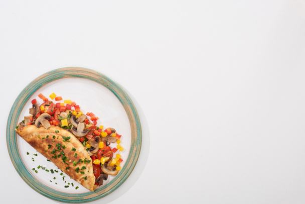 vrchní pohled na talíř s domácí omeletou s houbami a paprikou na bílém stole  - Fotografie, Obrázek