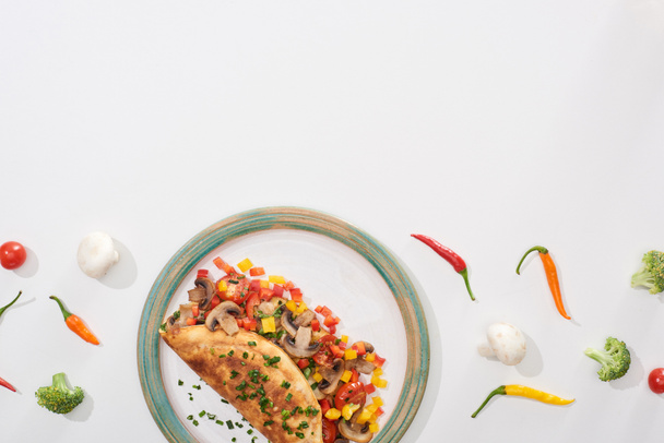 Draufsicht auf leckeres Omelett mit Gemüse auf Teller mit frischen Chilischoten und Brokkoli - Foto, Bild