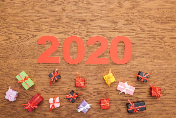 vista dall'alto di carta 2020 numeri vicino a piccole scatole regalo decorative su sfondo di legno
 - Foto, immagini