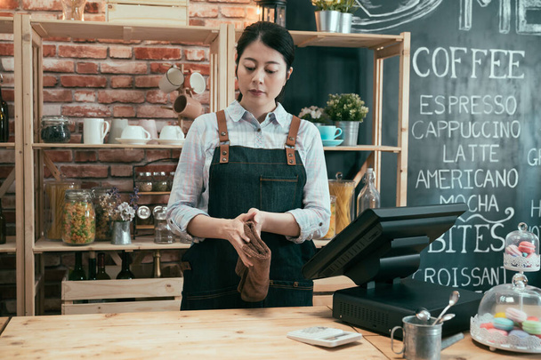 waitress behind cafe counter using cloth wiping - Photo, Image