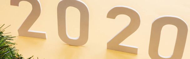 paper 2020 numbers near Christmas tree branch on yellow background, panoramic shot - Photo, image