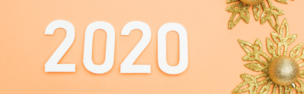 top view of white 2020 numbers near golden christmas decoration on orange background, panoramic shot - Foto, afbeelding