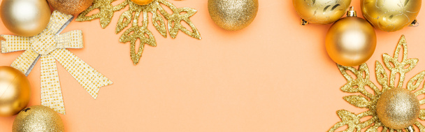 top view of golden Christmas decoration on orange background with copy space, panoramic shot - 写真・画像