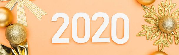 top view of white 2020 numbers near golden christmas decoration on orange background, panoramic shot - Photo, Image