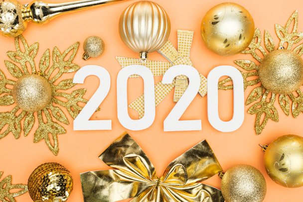 vrchní pohled na bílá 2020 čísla na zlaté vánoční dekorace na oranžovém pozadí - Fotografie, Obrázek