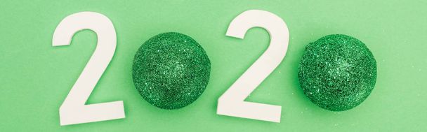 Yeşil zemin üzerinde noel mücevherleri olan beyaz 2020 rakamlarının üst görünümü, panoramik çekim - Fotoğraf, Görsel