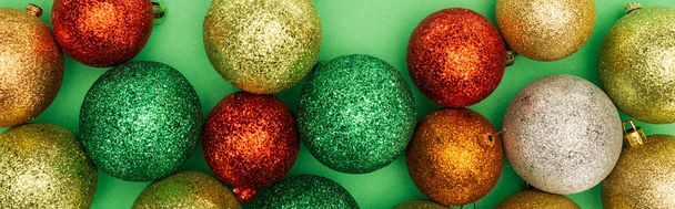 緑色の背景に多色の光沢のあるクリスマスボールの上からの眺めパノラマショット - 写真・画像