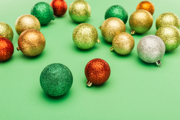 selective focus of multicolored Christmas baubles on green background - 写真・画像
