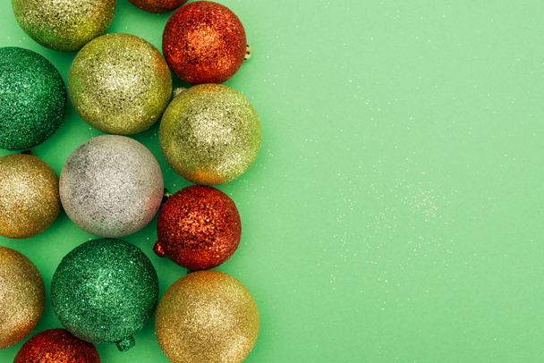 bovenaanzicht van kleurrijke kerstballen op groene achtergrond - Foto, afbeelding
