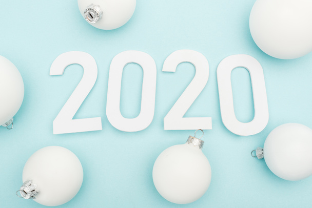 top view of white 2020 numbers near Christmas baubles on light blue background - Foto, immagini