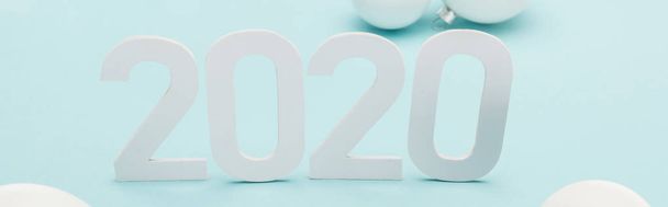 white 2020 numbers near Christmas baubles on light blue background, panoramic shot - Valokuva, kuva