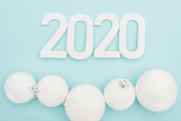 top view of white 2020 numbers near Christmas baubles on light blue background - Photo, Image