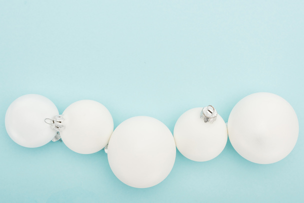 top view of white Christmas balls on light blue background with copy space - Foto, afbeelding