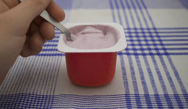 kéz megragad egy kanál enni egy málna joghurt - Fotó, kép