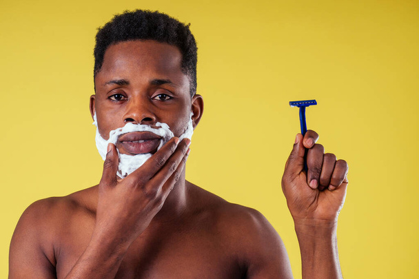 African-american man with razor and shaving foam on his face - Foto, Bild