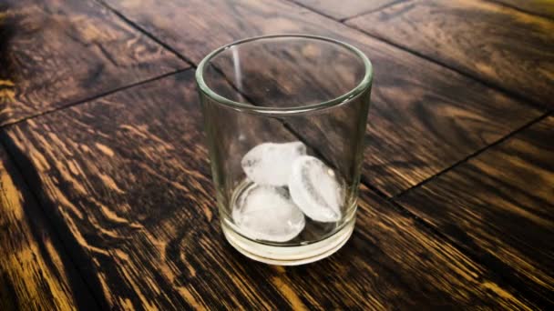 Cubos de gelo se movem em um vidro enevoado em um fundo de mesa
 - Filmagem, Vídeo