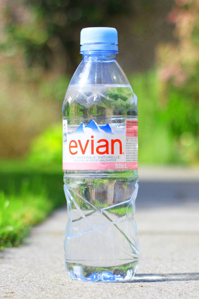 Bottle of Evian natural mineral water with sunny summer background - Valokuva, kuva