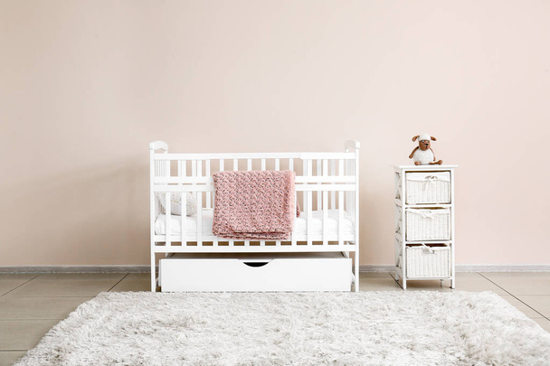 Stylish baby bed near light wall in interior of children's room - 写真・画像