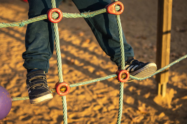 Хлопчик грає в парку, піднімаючись на сітку
 - Фото, зображення